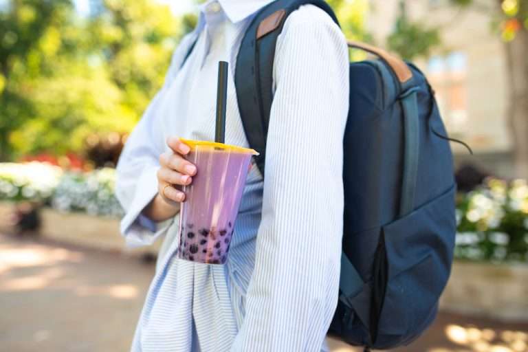 student poses with botrista ube powder boba milk tea on campus.
